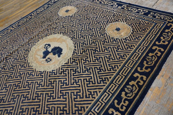 Navy and beige rug with interlocking geometric patterns, round medallions, and decorative borders on wood.
