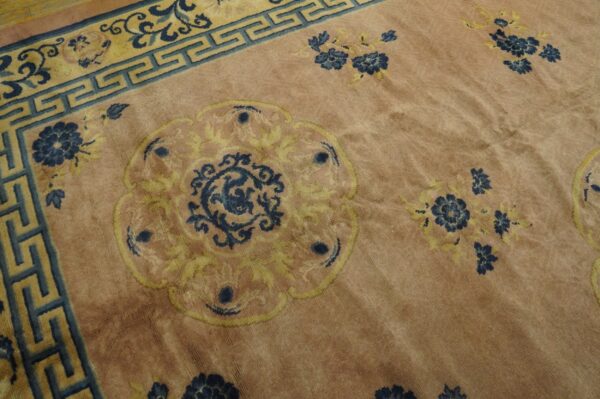 Plush pink rug showing a blue and yellow medallion pattern and a teal key border.