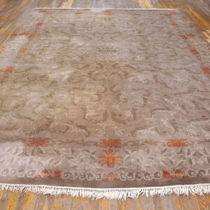 Traditional taupe rug with scrolling brown and rusty orange accents displayed on distressed hardwood flooring.