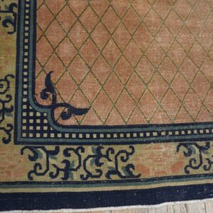 Pink trellis rug with detailed multi-colored border and navy accents visible on light wood floor.