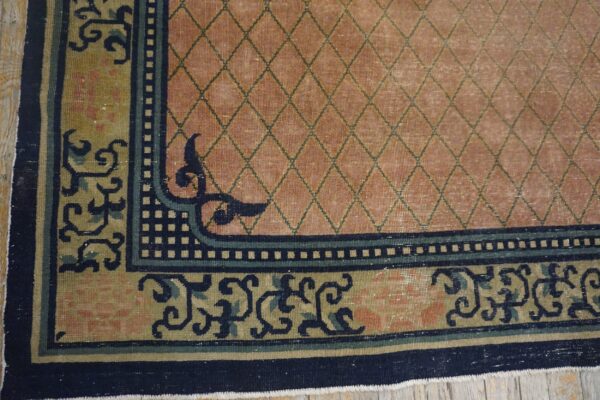 Pink trellis rug with detailed multi-colored border and navy accents visible on light wood floor.