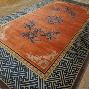 Terracotta rug with blue floral accents and a large blue geometric border pattern rests on wood flooring.