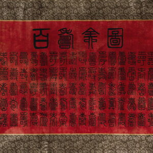 Red low-pile rug with black script and a wide border of dark gray swirling floral patterns.