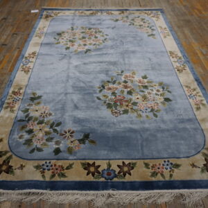Velvety blue rug featuring pale floral medallions, a tan border, and fringe on distressed wooden floors.