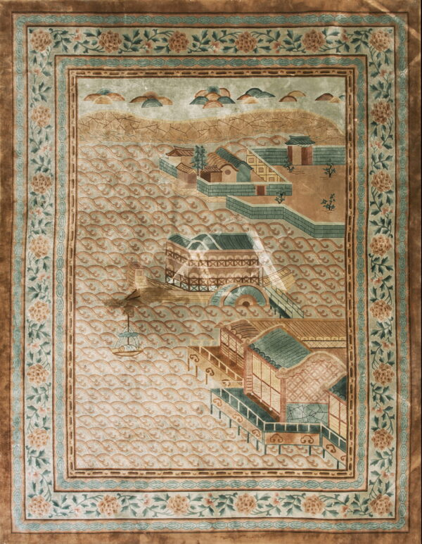 Muted green and tan pictorial rug depicting a waterfront village framed by wide floral borders.