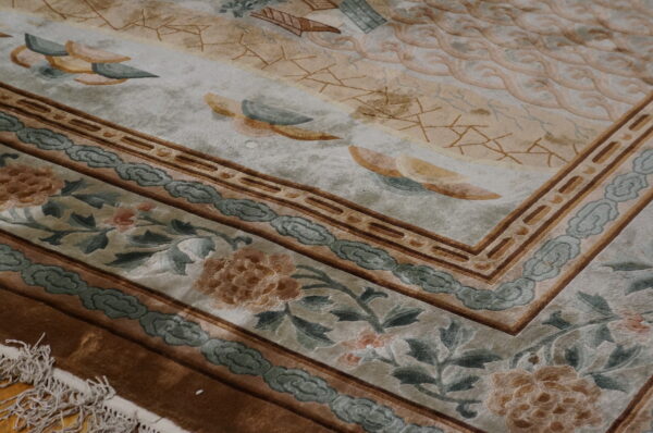 Textured rug detail with tan, beige, and teal borders featuring florals and cloud motifs.