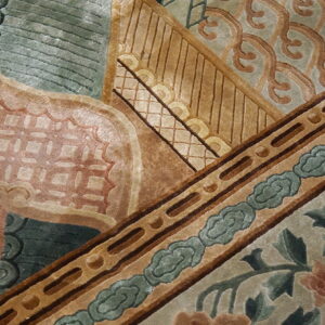 Close-up of a sculpted rug pattern featuring sage, tan, terracotta, and brown geometric and floral motifs.