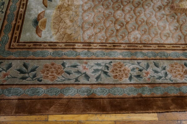 Sculpted, high-pile rug detail showing layered floral and cloud borders in sage green, tan, and brown on wood.