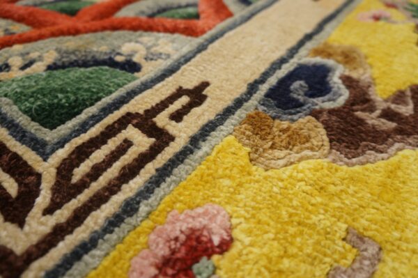 High-texture close-up of a colorful rug featuring yellow, green, red, brown, and blue geometric and abstract designs.