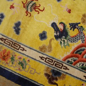 Textured yellow rug featuring a large blue dragon motif and intricate floral and geometric borders on wood planks.