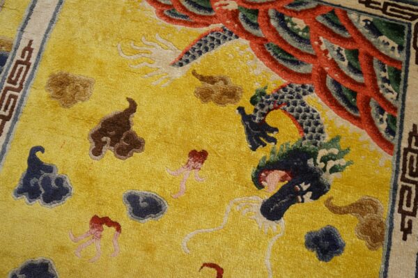 Textured yellow rug with detailed blue and red dragon motif and brown, dark blue cloud designs.