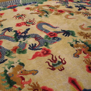 Gold rug with carved texture displaying intricate blue, brown, and red dragon motifs.