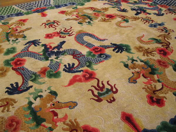 Gold rug with carved texture displaying intricate blue, brown, and red dragon motifs.
