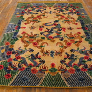 Yellow rug with blue and gold dragons and detailed red, green, and blue borders placed on wooden floorboards.