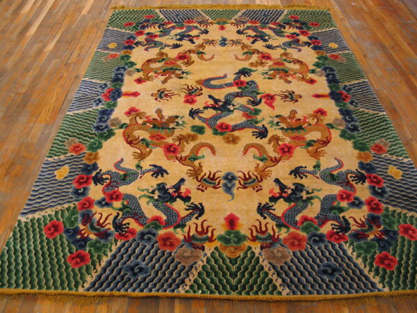Yellow rug with blue and gold dragons and detailed red, green, and blue borders placed on wooden floorboards.