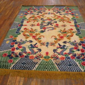 Colorful rug featuring dragons on a pale yellow field, bordered by green waves, with long visible golden fringe.