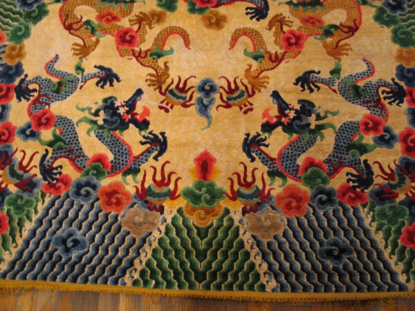 Multicolor rug featuring detailed gold and blue dragon motifs, clouds, and waves on a yellow background over wood flooring.