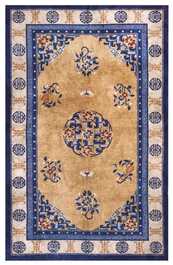 A golden tan rug with navy and beige borders features a central medallion and scattered blue floral sprays.