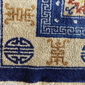 High pile blue, beige, and terracotta rug features borders with stylized Shou symbols and fringe.