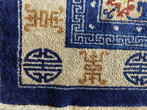High pile blue, beige, and terracotta rug features borders with stylized shou symbols and fringe.