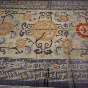 Ornate cream rug featuring dark gray fretwork borders and central floral motifs in orange, red, and slate.