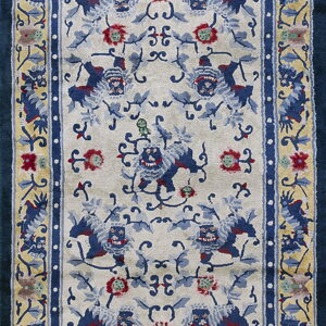 Ornate area rug featuring blue animal motifs and red flowers on an ivory field with gold and dark blue borders.