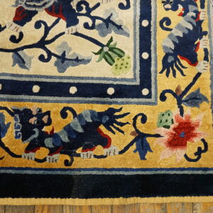 Ornate high-pile rug detail featuring navy, gold, and cream borders with dragon and floral patterns on wood flooring.