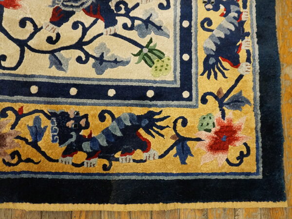 Ornate high-pile rug detail featuring navy, gold, and cream borders with dragon and floral patterns on wood flooring.