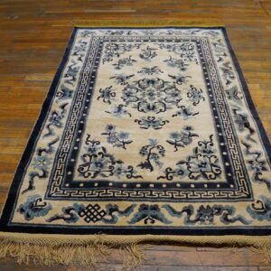 Plush cream rug with blue floral and geometric borders lying on polished wood floor.