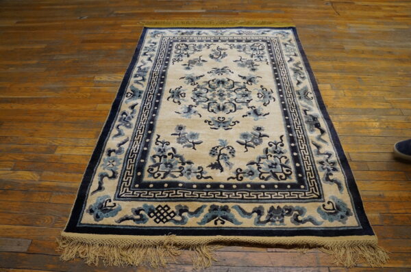 Plush cream rug with blue floral and geometric borders lying on polished wood floor.