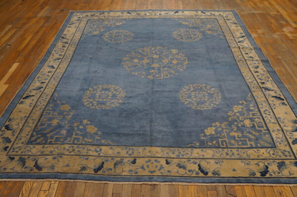 Denim blue rug with tan geometric and medallion patterns lying on a natural wood plank floor.