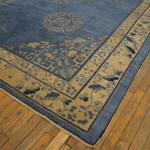 Medium pile blue and gold rug featuring detailed geometric borders rests on textured hardwood flooring.