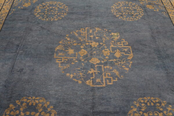 Blue rug surface detailed with sparse gold repeating floral and geometric medallion patterns.