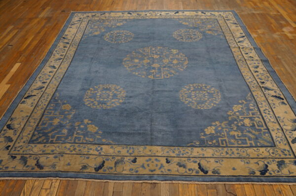 Blue rug featuring scattered gold medallions and complex borders rests on distressed hardwood flooring.