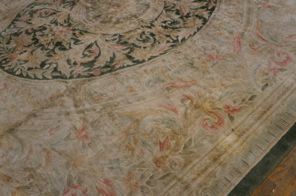 Carved low-pile rug featuring muted beige, moss green, and rose floral and scrolling botanical patterns.