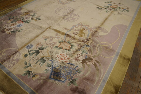 Lustrous beige rug displays detailed floral motifs and mauve accents on a rustic wood floor.