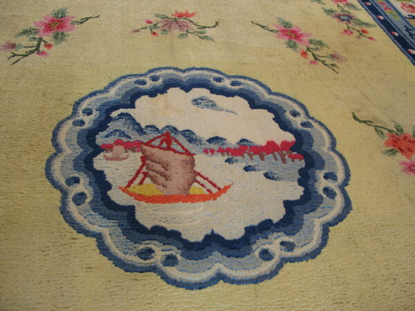 Pale yellow plush rug detailed with a blue landscape medallion and pink floral motifs.