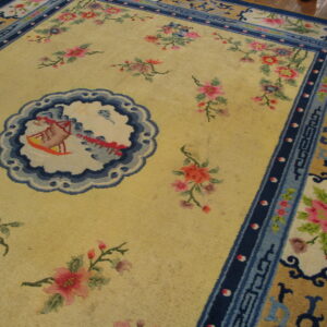 Low pile rug featuring a yellow field, pink flowers, and elaborate blue geometric and floral borders.