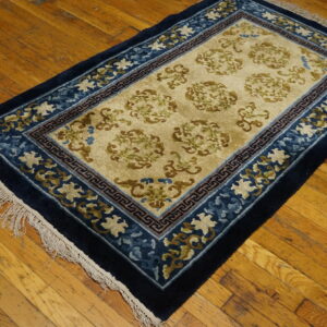 A navy blue and beige rug with scrolling floral patterns sits on a rustic wood floor.
