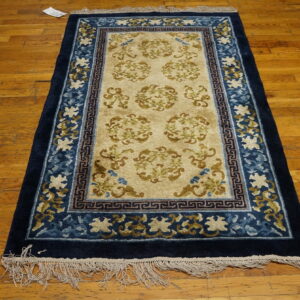 Navy and tan rug featuring scrollwork medallions and detailed blue borders rests on a plank hardwood floor.