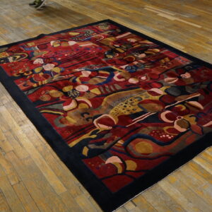 Sculpted abstract rug with red, yellow, and blue colors, bordered in black on rustic wood flooring.