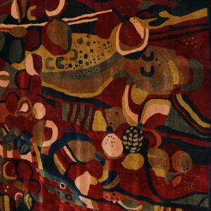 A deeply carved rug with an abstract pattern of organic forms in maroon, mustard, dark blue, and pink.