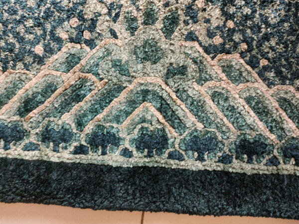 Close-up of a dimensional looped rug featuring an abstract mountain design in shades of teal and beige.