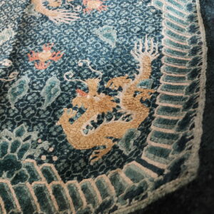 Highly textured teal rug with detailed golden dragon motifs, coral accents, and a stepped border design.