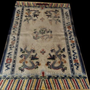 Intricate beige rug featuring blue dragon motifs, dark blue frame, and multicolored striped ends.