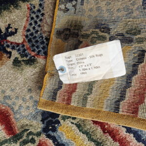 Detailed view of a tan, blue, and red patterned rug's high pile next to its woven, striped backing.