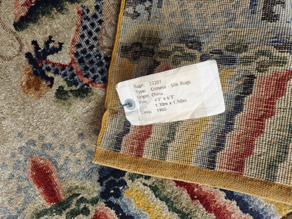 Detailed view of a tan, blue, and red patterned rug's high pile next to its woven, striped backing.