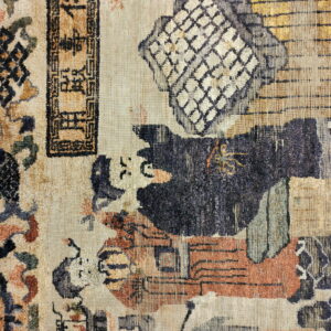 Worn rug detail with abstract figures, a beige ground, and accents of navy, rust, and gold on tile.