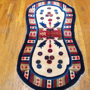 Contoured rug with a cream center, navy border, and colorful striped pattern lies on plank hardwood flooring.
