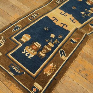 A dark blue and brown runner rug with stylized vessel patterns rests on distressed wooden floorboards.